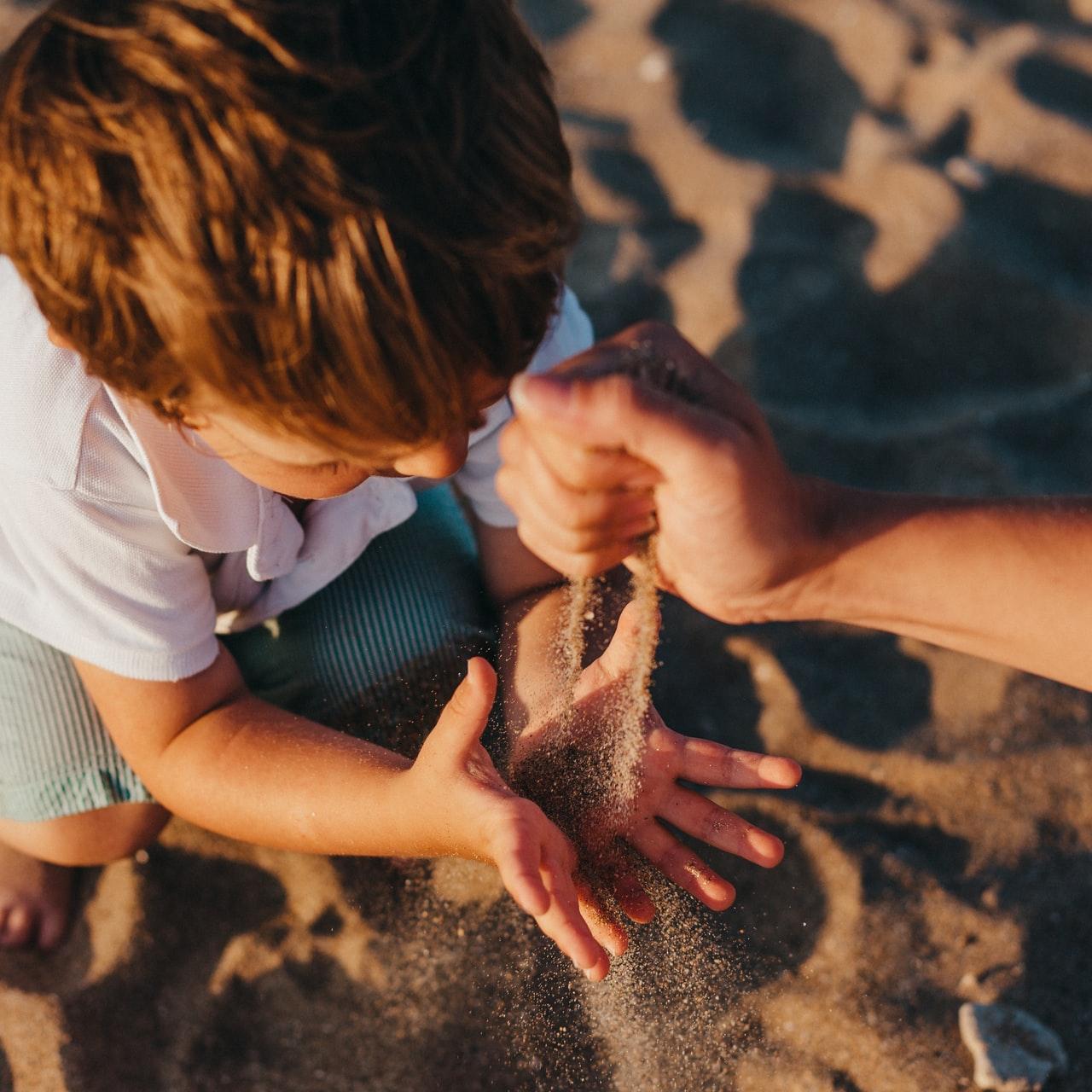 person pouring sand into boys hands